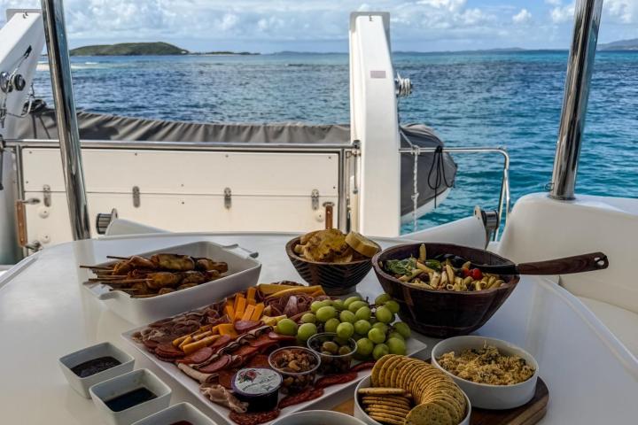 Charcuterie board and salads on boat table with ocean view.