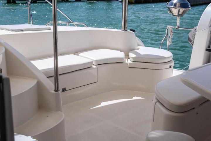 Empty boat deck with white seating and turquoise water in the background.