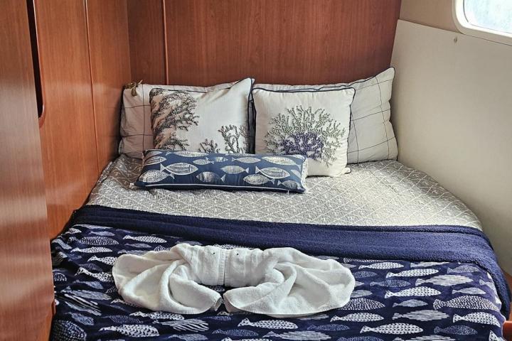 Cozy boat cabin with a bed, pillows, and a fish-patterned blanket.