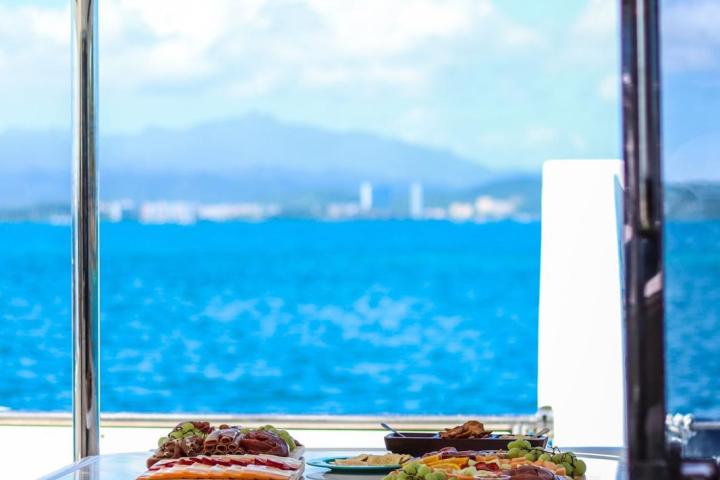 Table with food platters on a boat, ocean and mountains visible through windows.