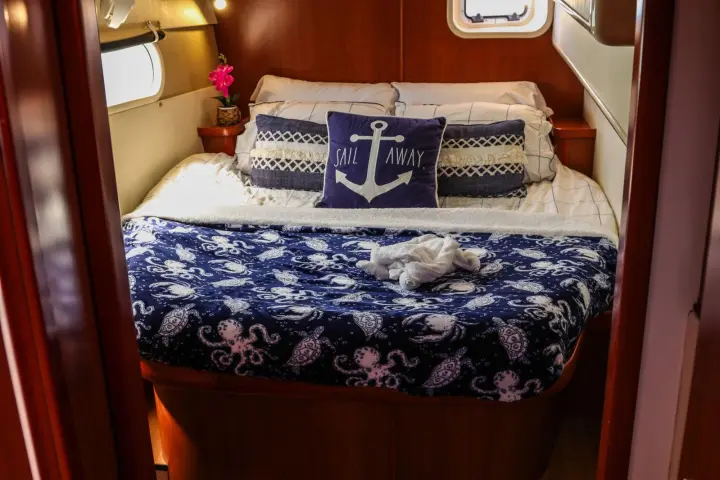 Cozy boat cabin with bed, anchor-themed cushion, and patterned blanket.