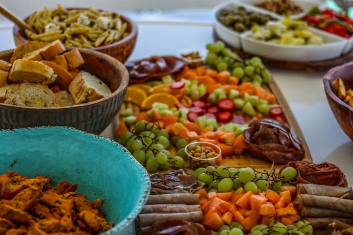 Variety of fruits, breads, meats, and cheeses on a table setting.